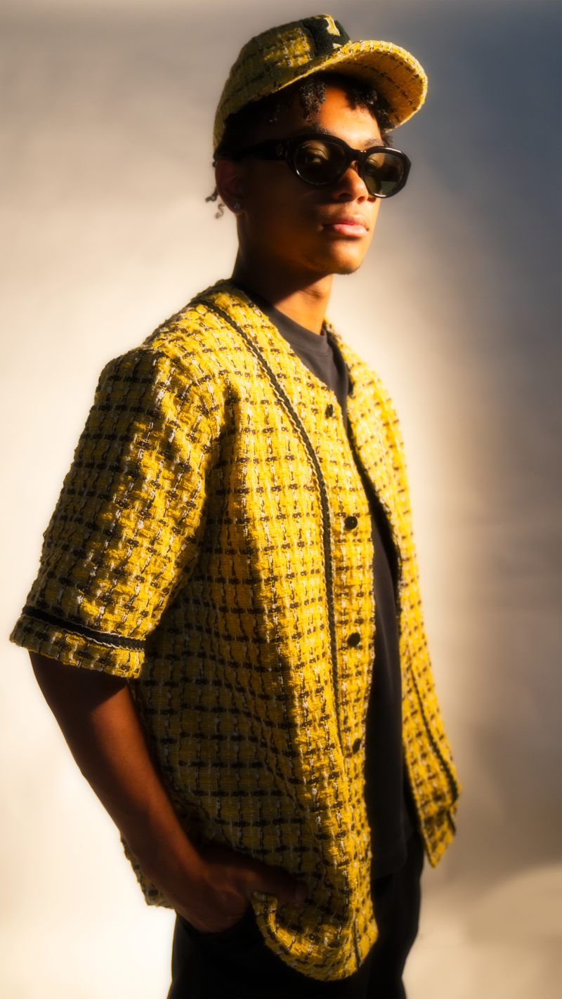 Person wearing a yellow patterned jacket and sunglasses against a neutral background
