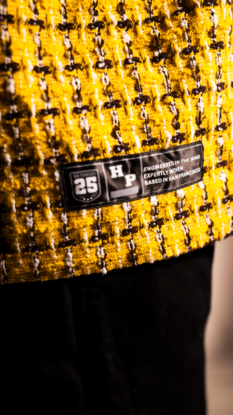 Close-up of a textured fabric with a brand label on a yellow and black patterned background.